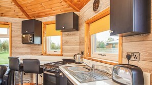 A modern kitchen with a gas stove, a built-in oven, a sink, and a toaster. There are two bar stools and a window with a view of the outdoors. - 1 bedroom accommodation in Fitling, Nr Hornsea (Fitling, Nr Hornsea)