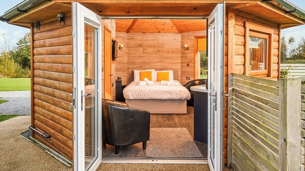 A log cabin-style bedroom with a bed, a chair, and a small desk. - 1 bedroom accommodation in Fitling, Nr Hornsea (Fitling, Nr Hornsea)