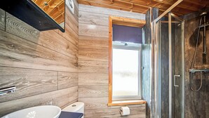 A modern bathroom with a wooden interior, a glass shower enclosure, and a window providing natural light. - 1 bedroom accommodation in Fitling, Nr Hornsea (Fitling, Nr Hornsea)