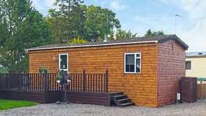 A small wooden cabin with a wooden deck and a fenced area. - Kinclaven (No Hot Tub) (Cargill)