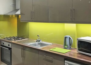 A kitchen with a gas stove, stainless steel sink, and a microwave.