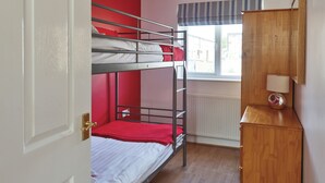A bunk bed room with a wooden cabinet and a window.
