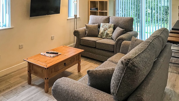 A living room with a sofa, a coffee table, a TV, and a window with blinds.