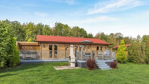 A wooden building with a red roof, a fenced patio area with outdoor seating, and a well-maintained lawn. - 2 bedroom accommodation in Ellesmere (Ellesmere)