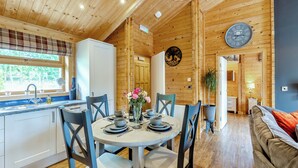 A wooden cabin interior with a dining area, kitchen, and living space. - 2 bedroom accommodation in Ellesmere (Ellesmere)