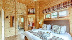 A wooden cabin bedroom with a bed, a window, a headboard, and a painting on the wall. - 2 bedroom accommodation in Ellesmere (Ellesmere)
