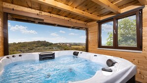 A hot tub with a scenic view of a forested hillside.