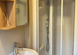 Baño con lavamanos, espejo y ducha.