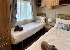 Quarto com cama de casal, mesa de cabeceira, abajur e guarda-roupa.