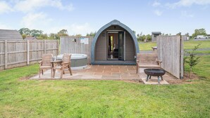 Un'area idromassaggio esterna accogliente con una terrazza in legno, una vasca idromassaggio e un tavolo da patio con sedie.