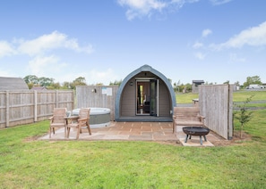 A cozy outdoor hot tub area with a wooden deck, a hot tub, and a patio table with chairs. - 0 bedroom accommodation in Great Busby (Great Busby)