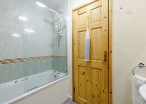 Un baño con ducha, bañera y puerta de madera.