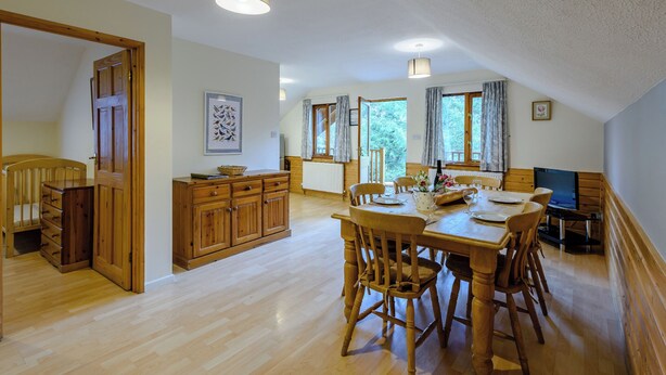 A spacious dining area with wooden furniture, a television, and a view of the outdoors.
