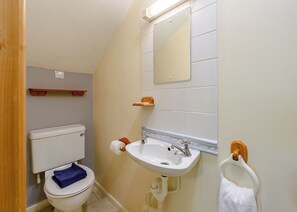 A bathroom with a toilet, sink, mirror, towel rack, and wooden shelf. - Timber lodge set in an elevated woodland position with views of the lake. (Webbery, Bideford)