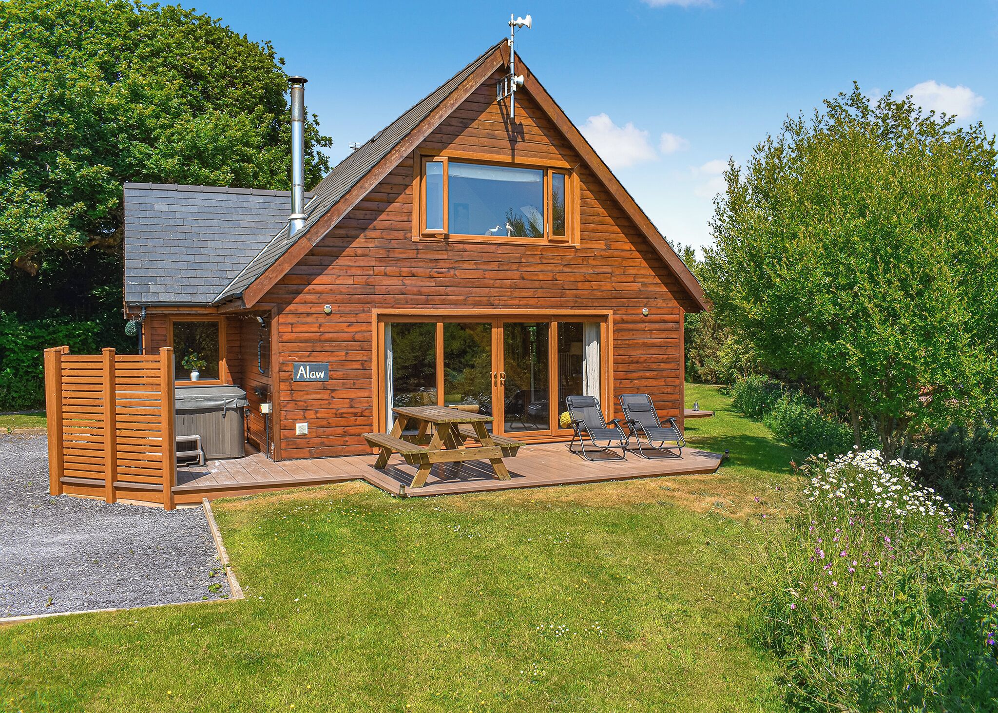 A wooden cabin with a patio, a hot tub, and a covered outdoor seating area.