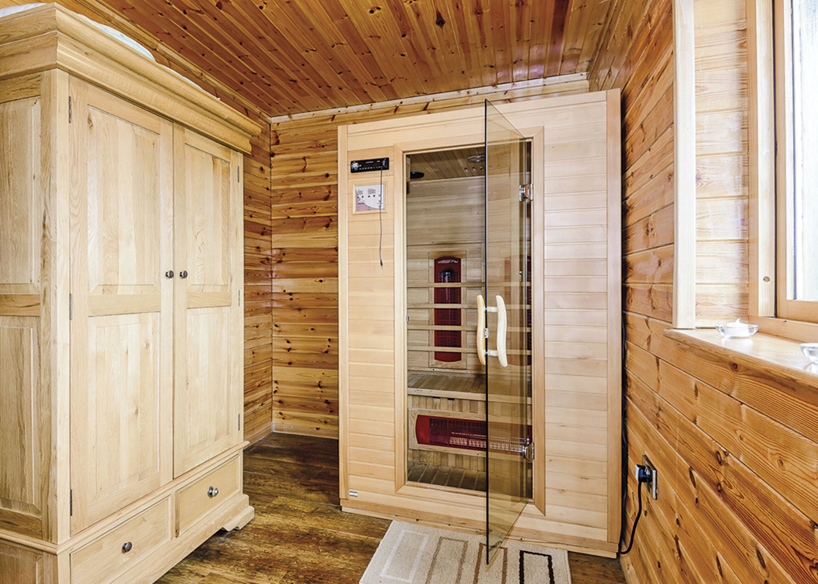 L’intérieur d’un chalet en bois, avec une armoire, un meuble vitré et une fenêtre.