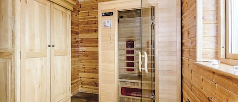 L’intérieur d’un chalet en bois, avec une armoire, un meuble vitré et une fenêtre.