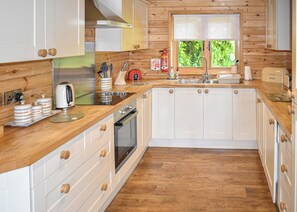 Una cocina moderna con armarios de madera, un lavamanos de acero inoxidable y un horno empotrado.