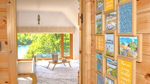 A wooden room with a bed, a small table with a basket, and a window with a view of greenery. - Perfectly positioned with panoramic views of the lake. (Anglesey)