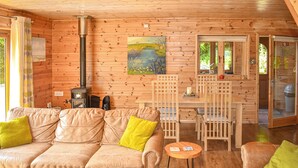 L’intérieur chaleureux d’un chalet avec un canapé en cuir, une table à manger en bois et un tableau accroché au mur.
