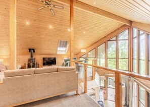 A wooden interior with a sofa, TV, fireplace, and large windows. - 3 bedroom accommodation in Millom (Millom)