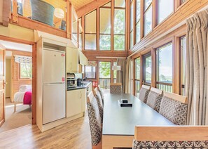 A cabin with a dining area, kitchen, and a cozy bedroom with a window.