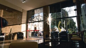 A lobby with large windows, a reception desk, and seating areas. - Lucape Palace Hotel (Barbacena)