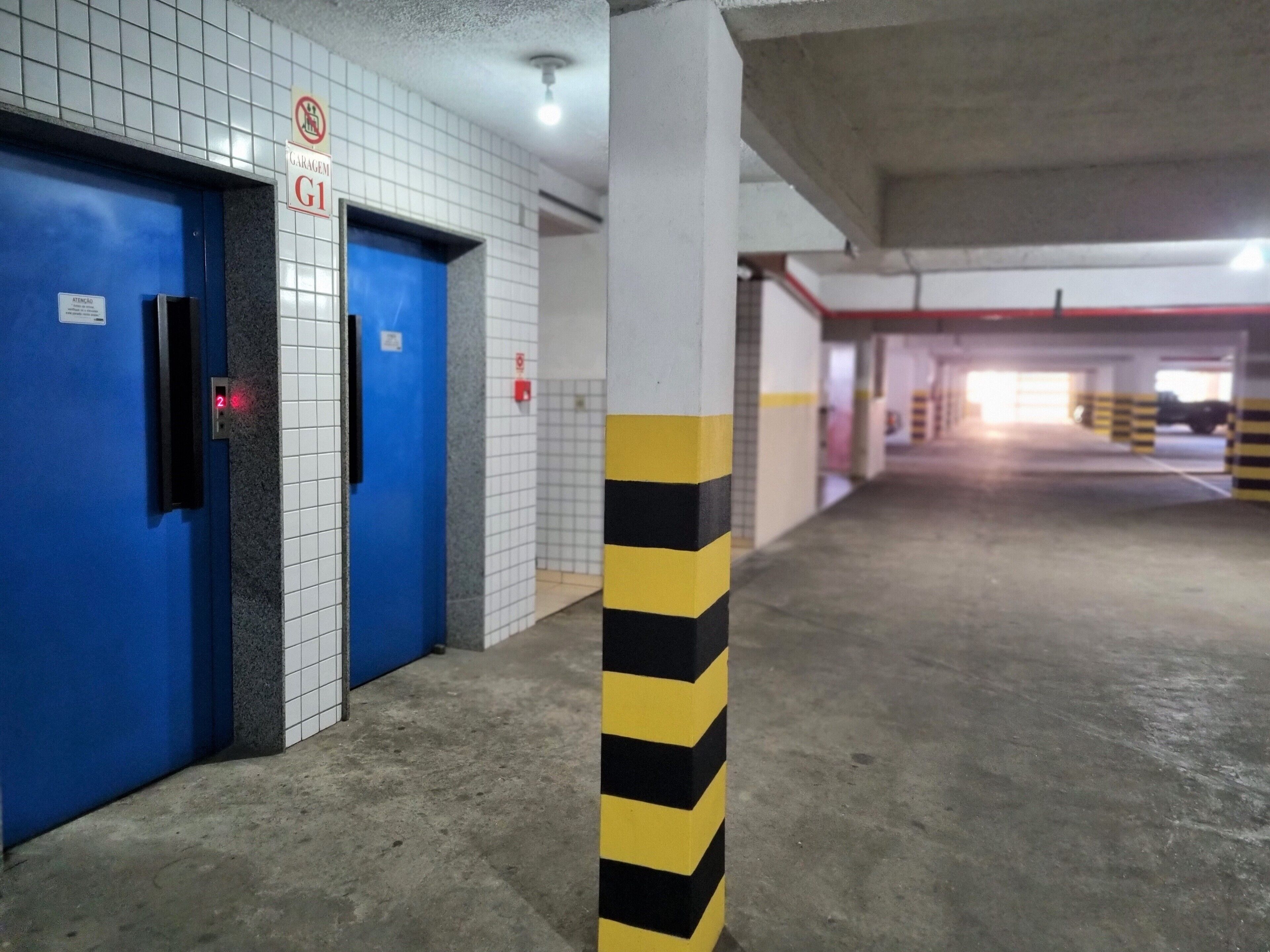A parking garage with blue doors, a garage sign, and yellow and black striped columns.