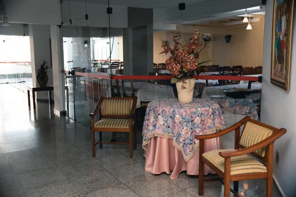 Un comedor con una mesa dispuesta para dos, sillas y un jarrón con flores.