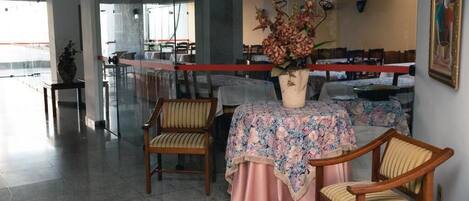 Un comedor con una mesa dispuesta para dos, sillas y un jarrón con flores.