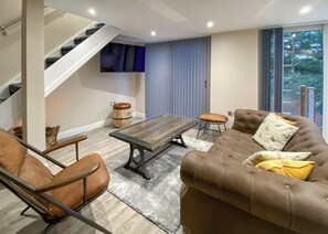 A modern living room with a sofa, a coffee table, a chair, a TV, and a staircase. - 1 bedroom accommodation in Water Yeat, Nr Coniston (Water Yeat, Nr Coniston)