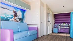 Ein modernes Wohnzimmer mit einem blau-violetten Sofa, einem großen Wandgemälde und einer violetten Sitzecke mit Tisch.
