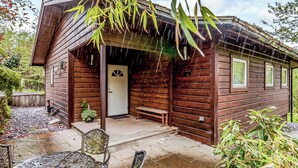 Une cabane en bois avec une véranda, un banc et une table.