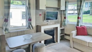 A compact living space with a kitchenette, a flat-screen TV, a dining table, and a sofa.