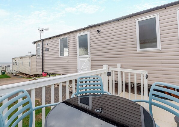 A mobile home with a deck, outdoor seating, and a window with a view.
