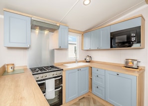 A compact kitchen with a gas stove, oven, microwave, and a toaster.