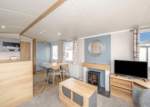 A compact living space with a kitchenette, dining area, fireplace, and a television.