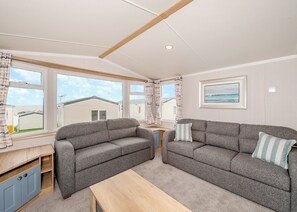 Ett mysigt vardagsrum med två grå soffor, ett soffbord i trä och en inramad tavla på väggen.