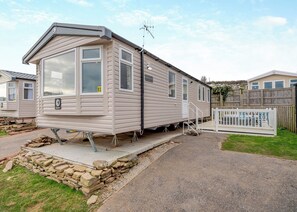 A mobile home with a front porch, a small deck, and a fenced backyard.