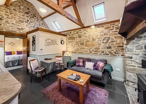 A cozy room with a stone wall, a bed, a dining table, and a sofa.