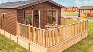 A wooden cabin with a balcony, large windows, and a door leading to an interior space. - Contemporary lodge furnished to a very high standard. (Tunstall, Nr Hull)