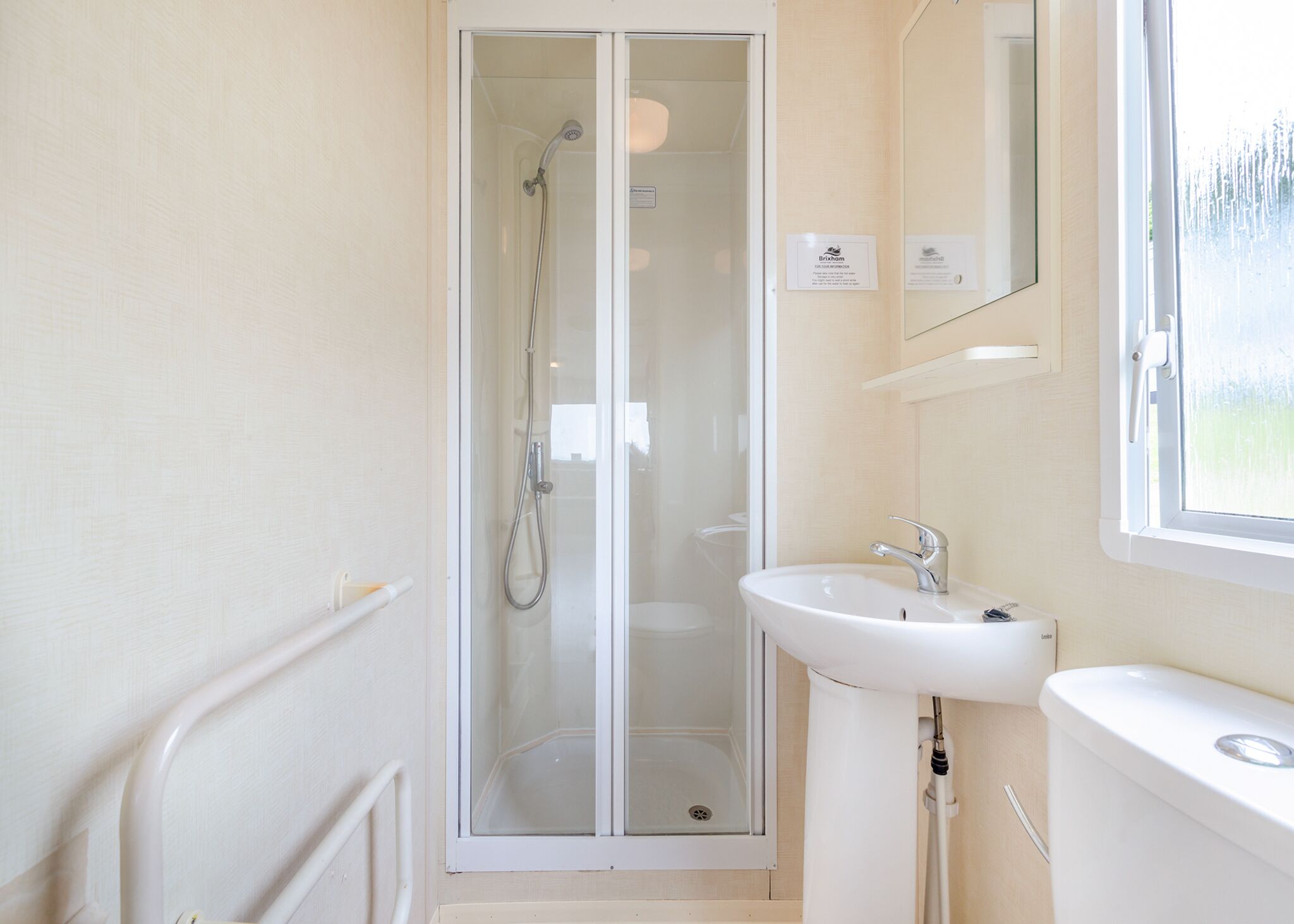 Une salle de bain avec une douche à parois de verre, un lavabo blanc et des toilettes.