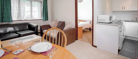 Un espacio habitable compacto con comedor, kitchenette y un dormitorio.