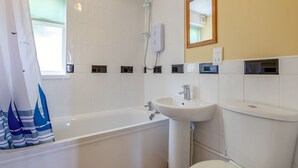 Et badeværelse med badekar, vask, toilet og brusehoved.