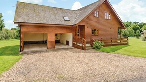 A wooden cabin with a garage, a covered porch, and a gravel driveway.