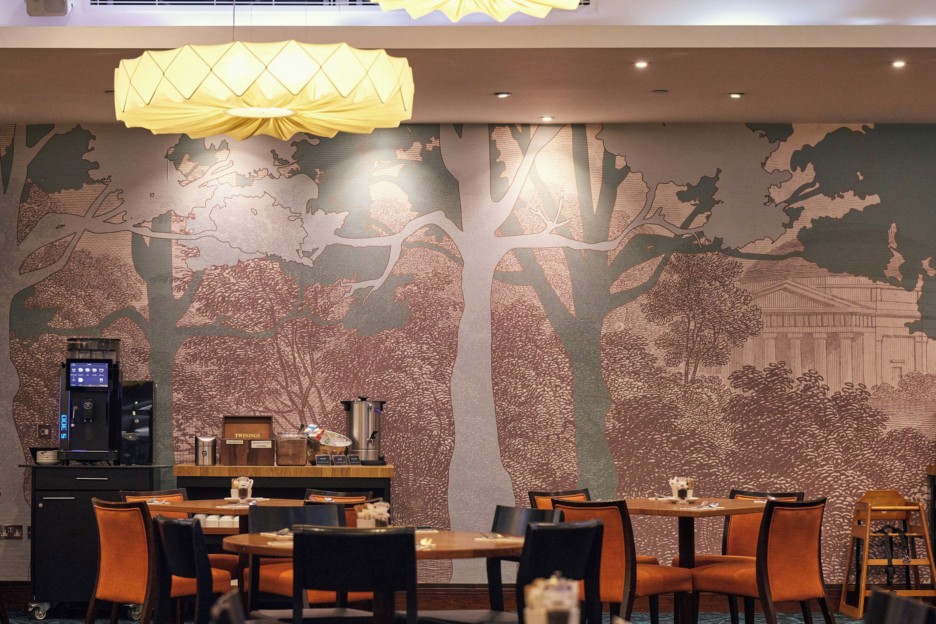 A restaurant with a mural of trees and a coffee machine.
