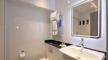 Uma casa de banho moderna com lavatório branco, espelho e suporte para toalhas.