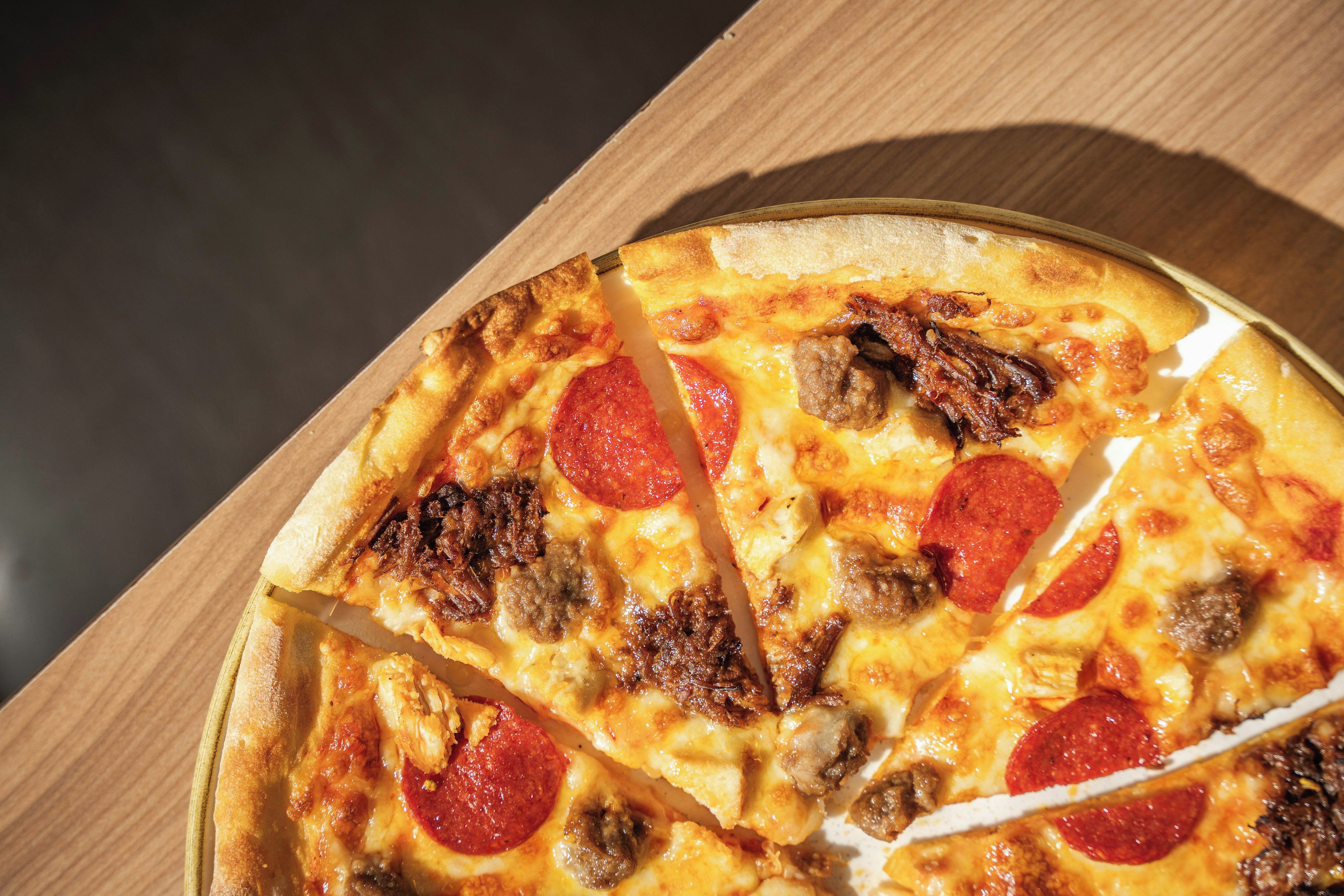 A pizza with pepperoni and sausage toppings on a wooden surface.