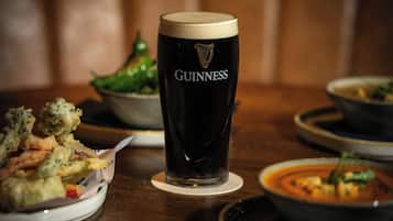 Un bicchiere di Guinness, una ciotola di zuppa e un piatto di cibo fritto su un tavolo.