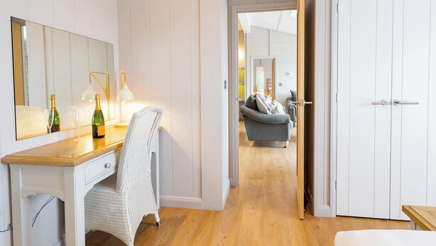 A hallway with a wooden desk, a wicker chair, a mirror, and a door leading to another room. - 2 bedroom accommodation in Cannington (Cannington)
